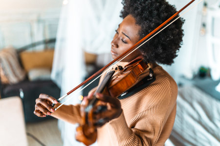 Attractive young african american woman musician plays the violin practicing musical instrumentの写真素材