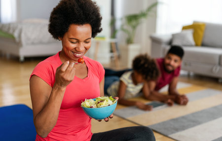 African american woman with family on background eating a healthy salad after workout. Fitnessの写真素材