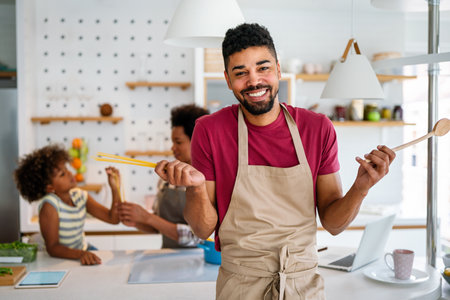 Happy african american family preparing healthy food in kitchen, having fun together on weekendの写真素材