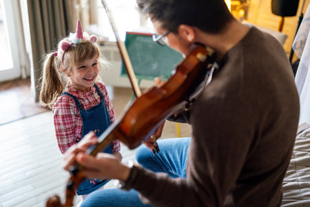 Music is so much fun. Young father teaching his little daughter to play violin and smiling.の写真素材