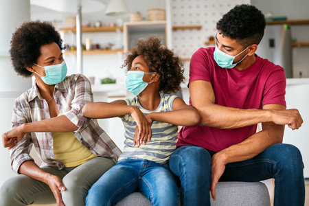 African american family in protective medical masks in the midst of the coronavirus pandemic at homeの写真素材