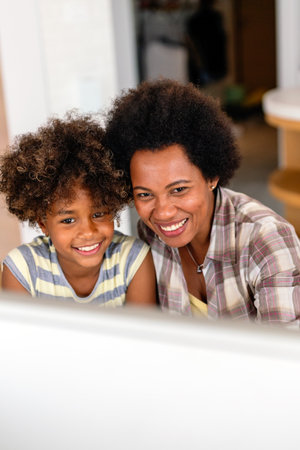Happy african american single mother helping child with distance education. Online education