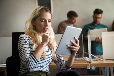 Confident and successful. Confident young woman in startup business office holding digital tabletの写真素材