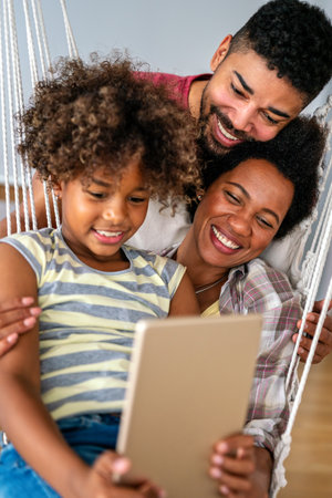 Happy african family having fun with device at home, black parents and child using digital tablet