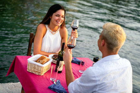 Couple in love drinking champagne wine on romantic dinner at sunset on the beach