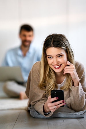 Smiling young woman chatting in social networks, working, using mobile applications at home.