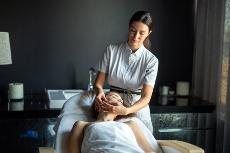 Face massage. Close-up of young woman getting spa massage treatment at beauty spa salon.の写真素材