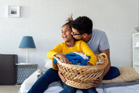 Black daughter helping father do household and domestic chores togetherの写真素材
