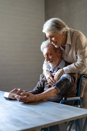 Happy senior couple measuring blood pressure at home