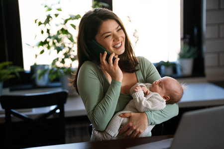Stay at home mom working remotely on laptop while taking care of her baby. Global work on computerの写真素材