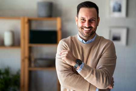 Satisfied with work done. Happy young man working on laptop while sitting at his working placeの写真素材
