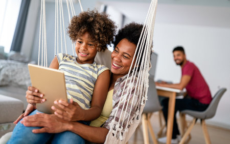 African american mother and daughter watching entertainment on digital tablet at homeの写真素材