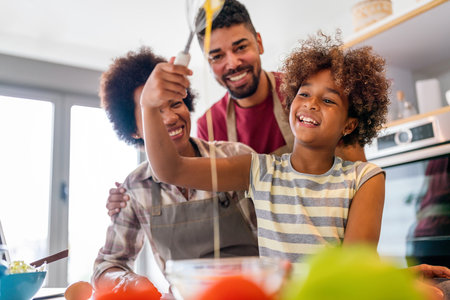 Overjoyed young african american family with kid have fun cooking at home together,の写真素材