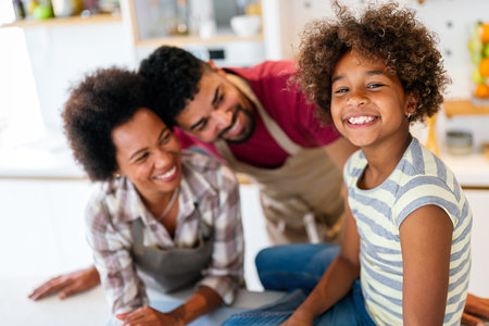 Overjoyed young african american family with kid have fun cooking at home together,の写真素材