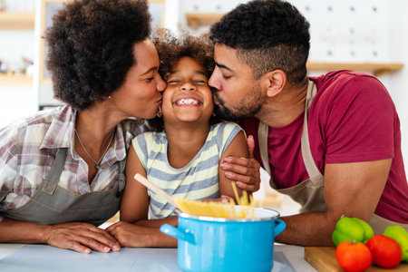 Happy black family in the kitchen having fun and cooking together. Healthy food at home.の写真素材