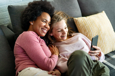 Happy african american mother and teen daughter using smartphone apps for shopping social mediaの写真素材