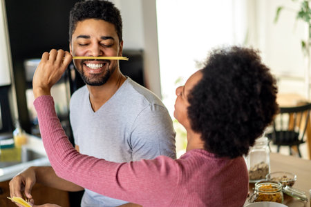 Happy young black couple have fun in modern kitchen while preparing fresh foodの写真素材