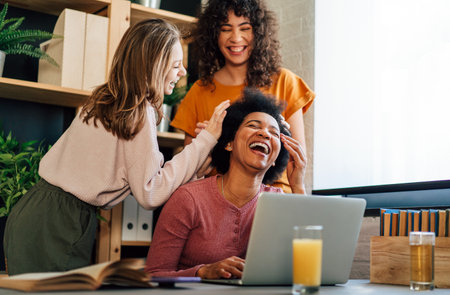 Black mother using computer and trying to focus on work while her teenager children disturb herの写真素材