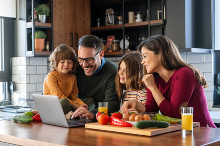 Happy parents at the kitchen counter with their children at home, enjoying weekend togetherの写真素材