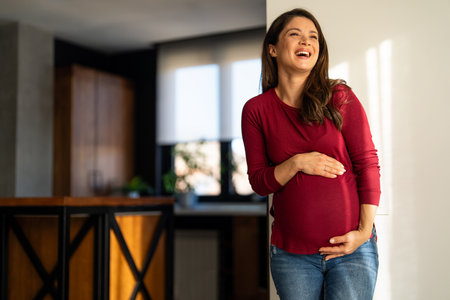 Fit pregnant woman holding hands on her belly, enjoying in the last trimester of pregnancy.の写真素材