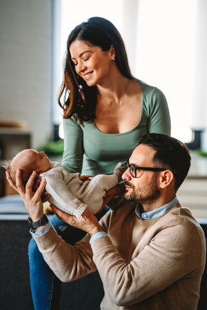 Portrait of young happy man and woman holding newborn cute babe dressed in white unisex clothing.の写真素材