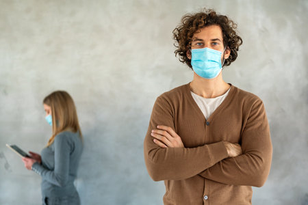People in business style and medical masks standing with gadgets and keeping social distance.の写真素材