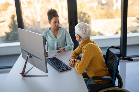 The image includes a person using a wheelchair, depicting inclusivity and teamwork in modern officeの写真素材