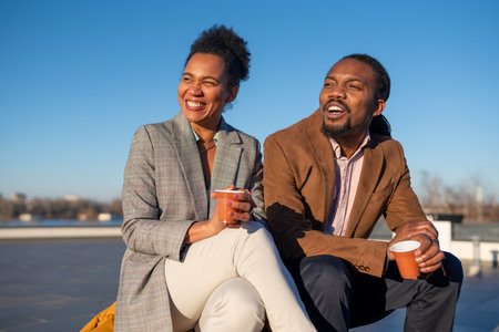 Mid-adult multiethnic business executives enjoy a sunny coffee break on top an office buildingの写真素材