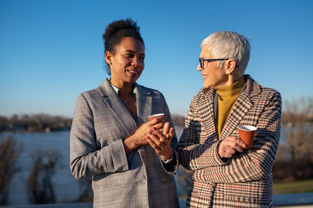 Team of multiracial successful business women on their way to the office talking, drinking coffeeの写真素材