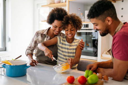 Happy african american family preparing healthy food in kitchen, having fun together on weekendの写真素材