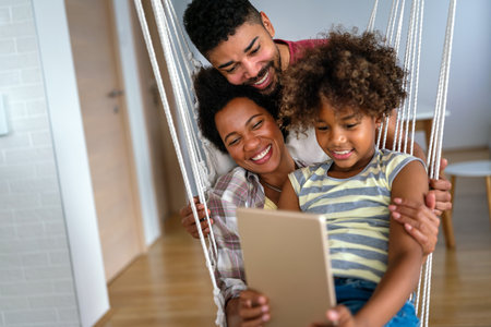 Happy african family having fun with device at home. Black parents and child using digital tabletの写真素材