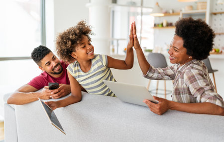 Happy african american family using digital tablet, computer, smartphonesの写真素材