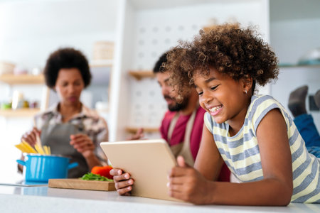 Happy smiling african american parents enjoy weekend play with child in kitchen.の写真素材