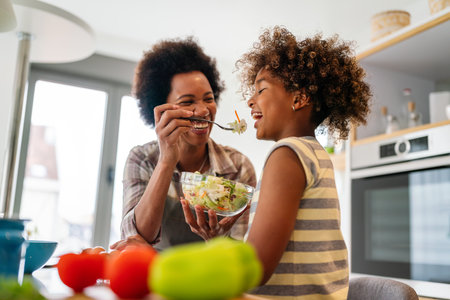 Healthy eating family and people concept. Happy mother and daughter having breakfast at home kitchenの写真素材