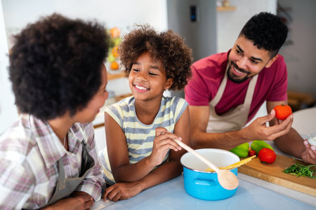 Overjoyed young african american family with kid have fun cooking at home together,の写真素材
