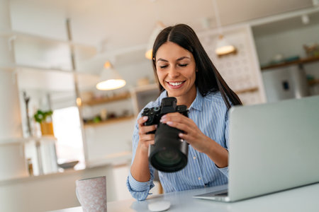 Happy photographer creative woman working in office with camera and laptop. Design startup concept.の写真素材