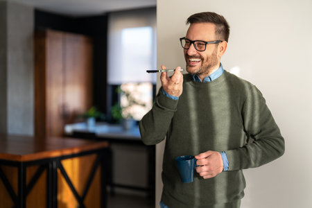 Confident smiling man using smartphone in a home office. Checking new e-mails, video callの写真素材