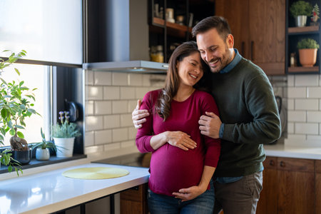 Beautiful pregnant woman and her handsome husband are smiling while spending time togetherの写真素材