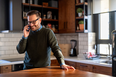Smiling businessman wearing casual clothes and using modern smartphone in his homeの写真素材