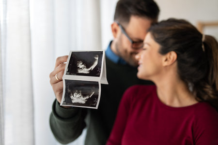 A couple sharing a tender moment while holding ultrasound photosの写真素材