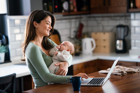 Stay at home mom working remotely on laptop while taking care of her baby.の写真素材