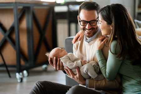 Smiling mother and father holding their newborn baby daughter at homeの写真素材