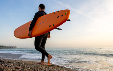 Happy young man is carrying surfboard walking on the beach. Sport, people, summer vacation conceptの写真素材