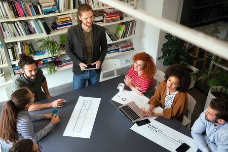 Smiling diverse colleagues gather in boardroom brainstorm discuss financial statistics togetherの写真素材