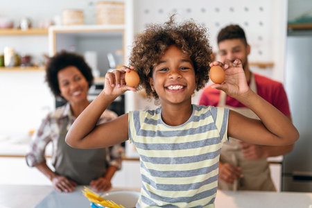 Happy black family in the kitchen having fun and cooking together. Healthy food at home.の写真素材