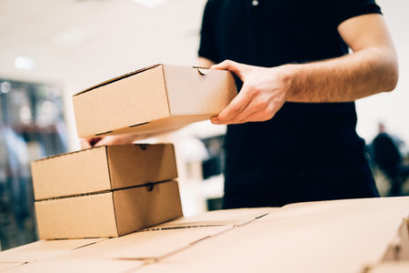 Young delivery man holding and carrying card boxの写真素材