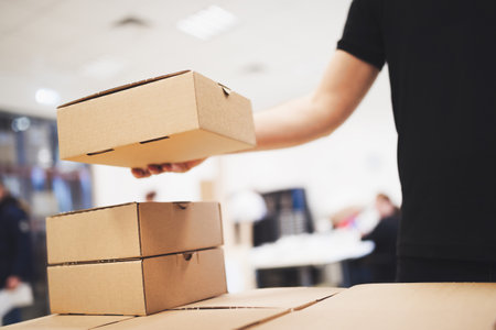 Young delivery man holding and carrying card boxの写真素材