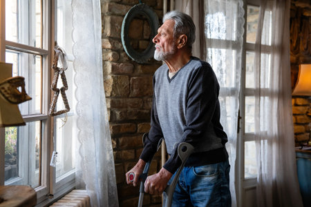 Upset thoughtful retired single man at home or nursing home alone with crutch , feels abandoned,の写真素材