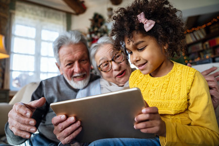 Happy senior couple using modern tech gadget together with grandchild at home.の写真素材
