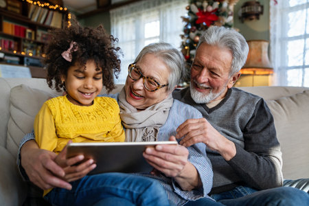 Happy senior couple using modern tech gadget together with grandchild at home.の写真素材